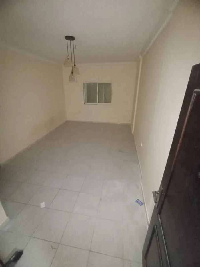 A happy room and a hall for annual rent in the Sanaiya area in Ajman, with multiple features such as a spacious hall, a modern design, 24-hour services and a vital area. We add central air conditioning, a kitchen with a balcony, and free parking, in  : Image 1